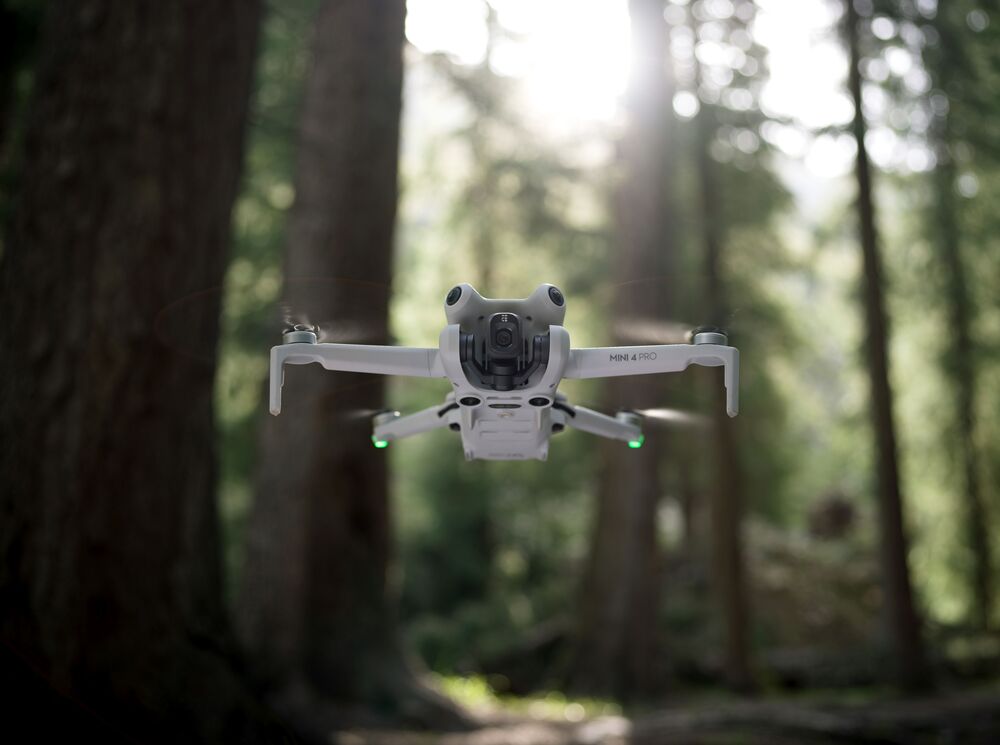 DJI Mini 4 Pro flying in a wooded area (real estate drone option)