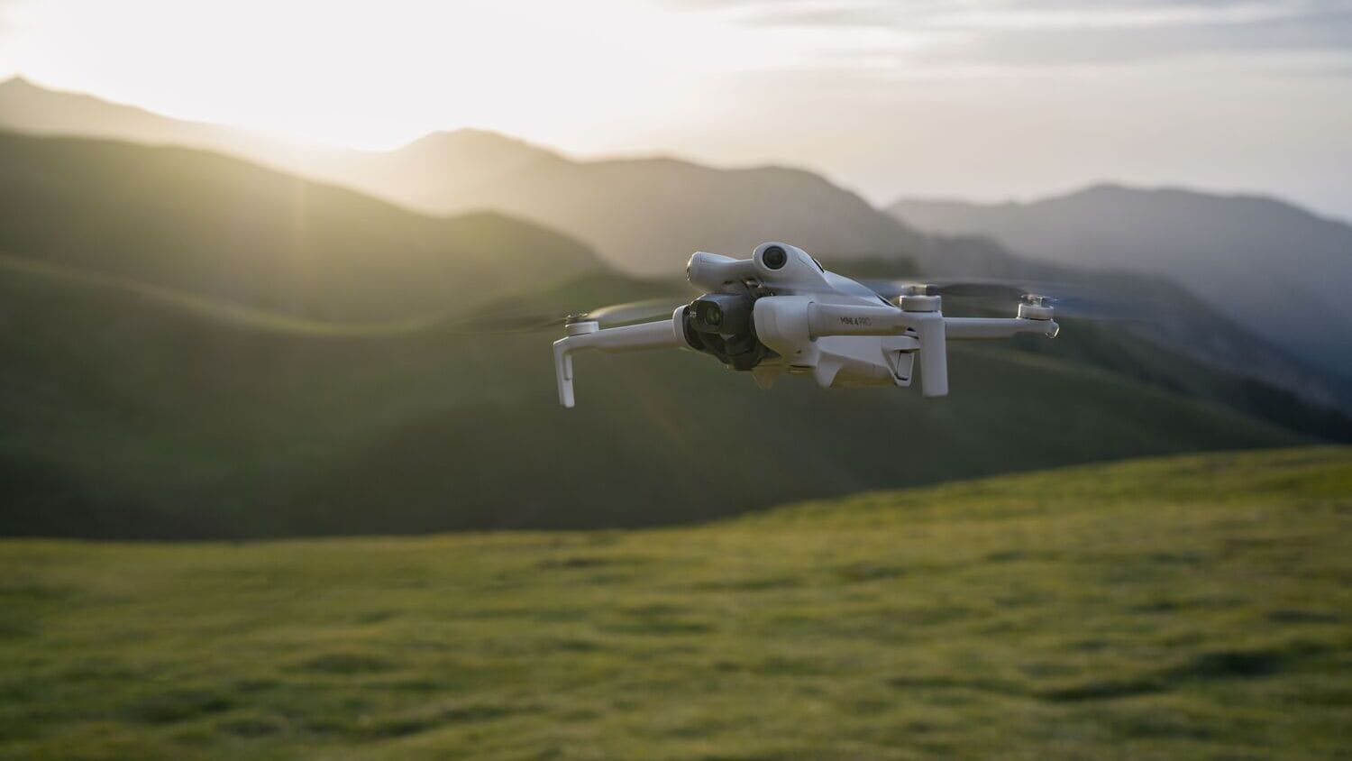 best drones for beginners 2026: DJI Mini 4 Pro flying over mountains at sunrise