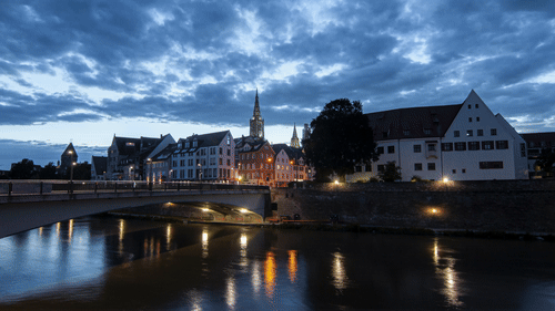 timelapse stock footage earnings: timelapse of a riverside city at blue hour with lights reflecting on the water